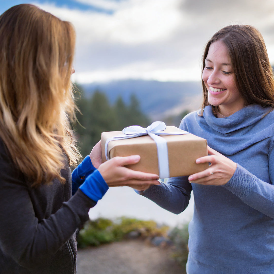 two women exchanging a wrapped gift