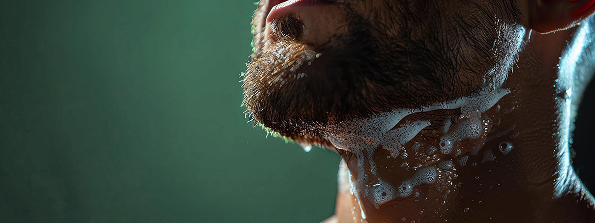 Close-up of a person with soap suds on their face against a green background