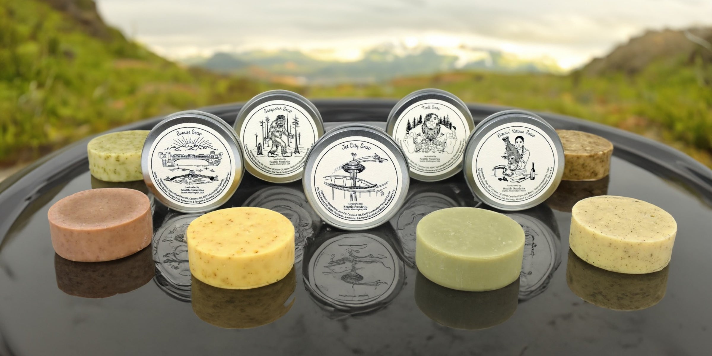Collection of soaps and containers on a reflective surface with a scenic background